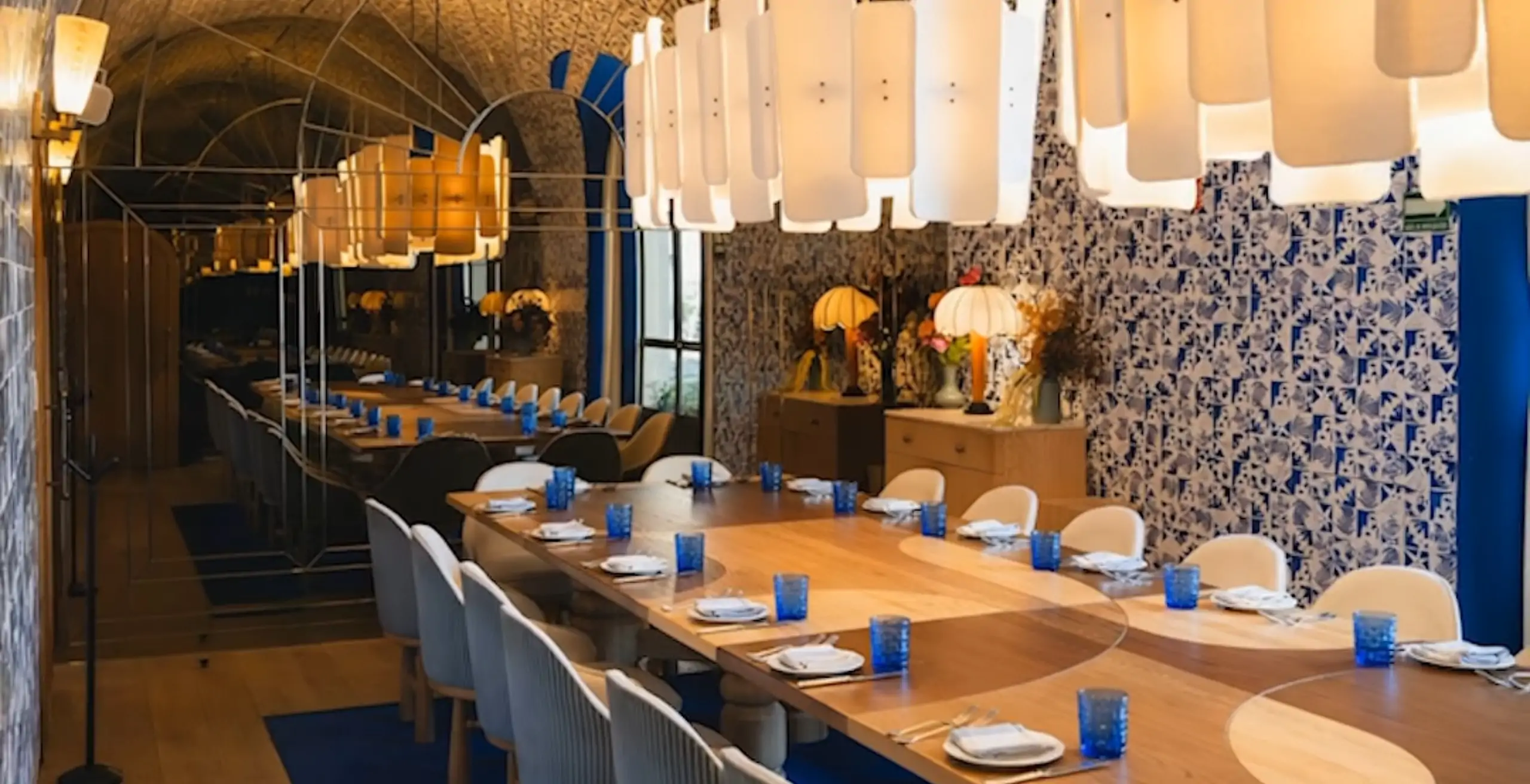 Elegant private dining room with a long table and striking blue glassware, showcasing event spaces manageable via OpenTable Private Dining.