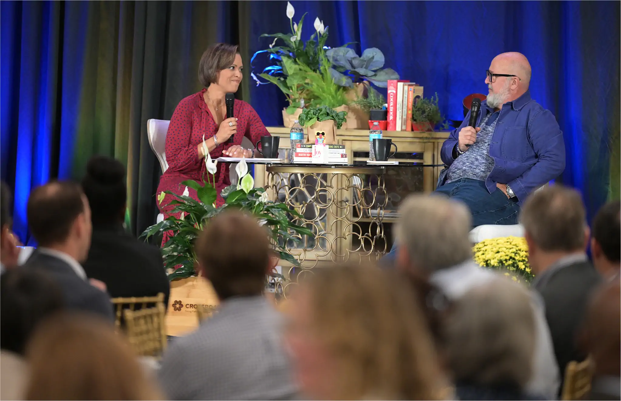 Author Andrew Zimmern speaking on stage with a microphone during an industry event, sharing his insights on the food world with an audience.